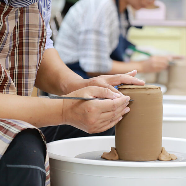 2 people making pottery from clay